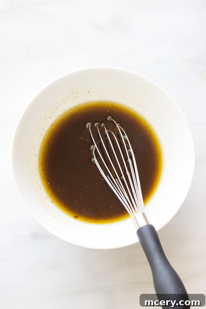 Mediterranean Chicken Quinoa Medley 7 whisked balsamic dressing in a white bowl with a whisk.