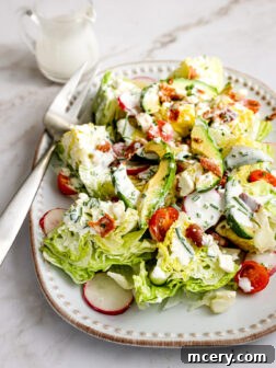 A perfectly portioned chopped iceberg lettuce salad with tomatoes, radishes, and bacon, ready to be served.