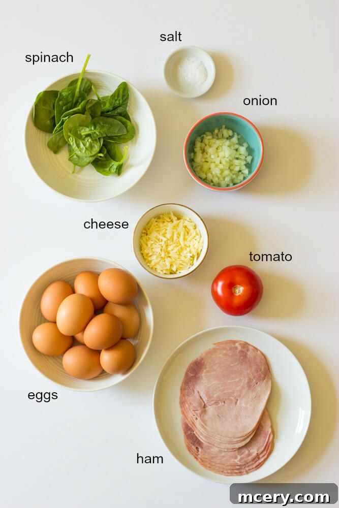 Savory Ham and Egg Breakfast Bites 3 A vibrant selection of fresh ingredients including eggs, ham, spinach, tomatoes, onions, and cheese, laid out on a kitchen counter, ready for preparing ham and egg muffin cups.