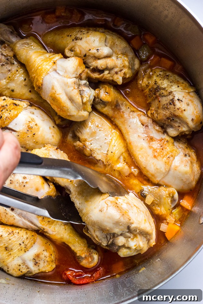 Simple Weeknight Chicken Cacciatore 8 chicken drumsticks inside sauce in a dutch oven.