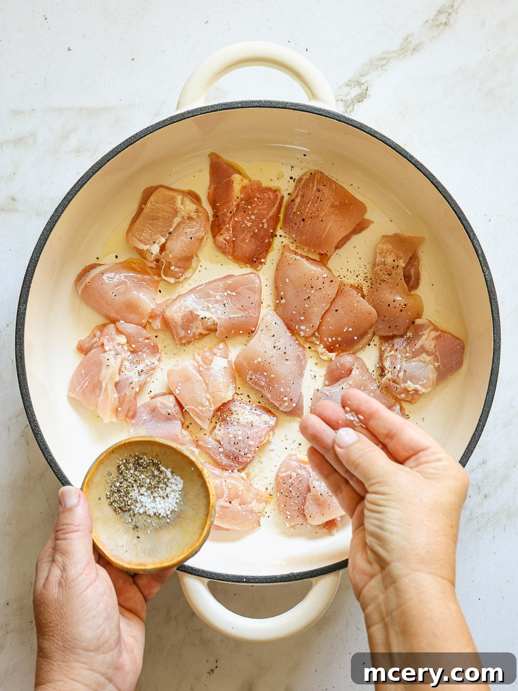 chicken pieces in a skillet with salt and pepper.